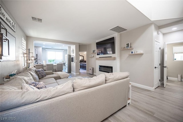 living room with a large fireplace and wood-type flooring