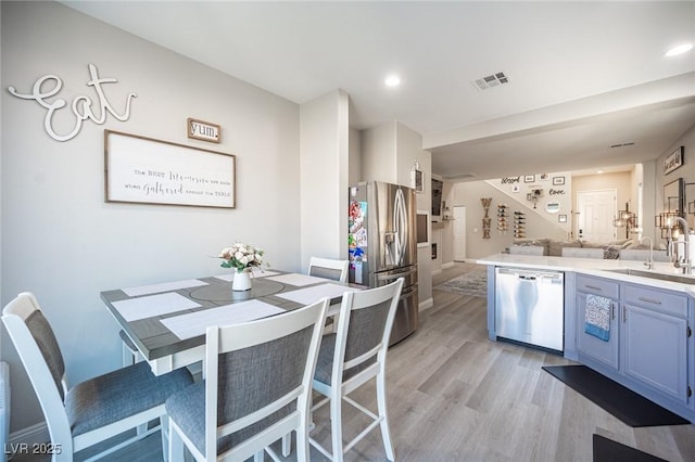 kitchen featuring kitchen peninsula, stainless steel appliances, light hardwood / wood-style flooring, and sink