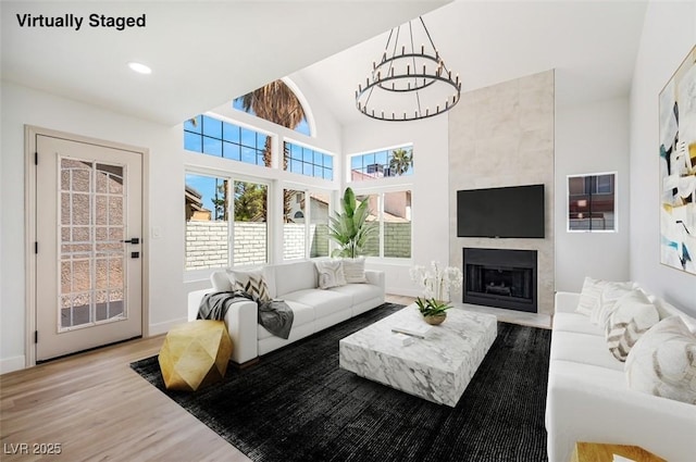 living room featuring a large fireplace, a notable chandelier, light hardwood / wood-style floors, and lofted ceiling