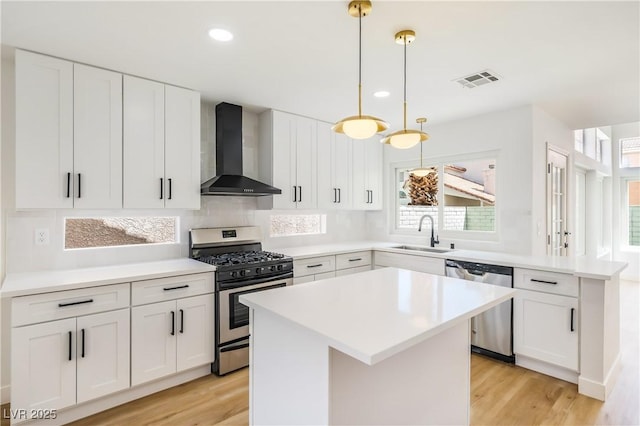 kitchen featuring sink, white cabinetry, a center island, wall chimney exhaust hood, and appliances with stainless steel finishes