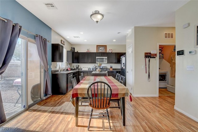 dining area featuring light hardwood / wood-style floors, washer / clothes dryer, and sink