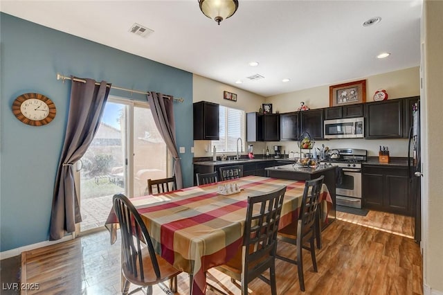 dining room featuring sink, light wood-type flooring, and plenty of natural light