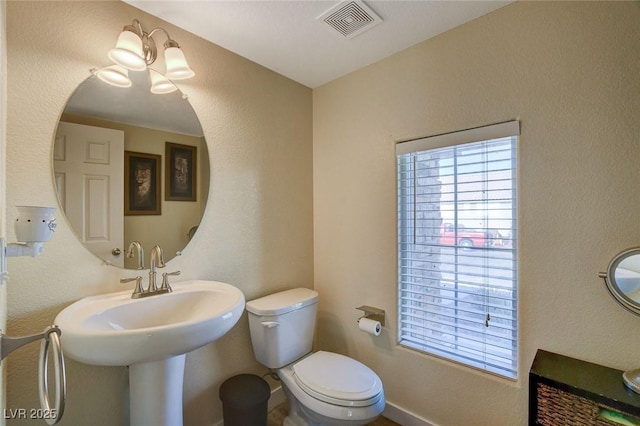 bathroom with toilet, an inviting chandelier, and sink