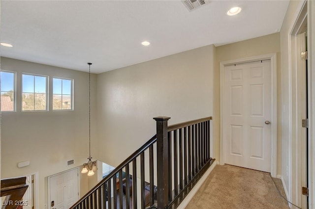 corridor with light colored carpet and an inviting chandelier