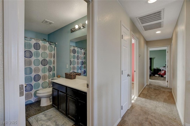 bathroom with walk in shower, vanity, and toilet