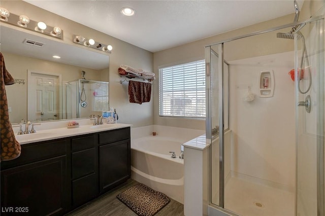 bathroom with wood-type flooring, vanity, and plus walk in shower