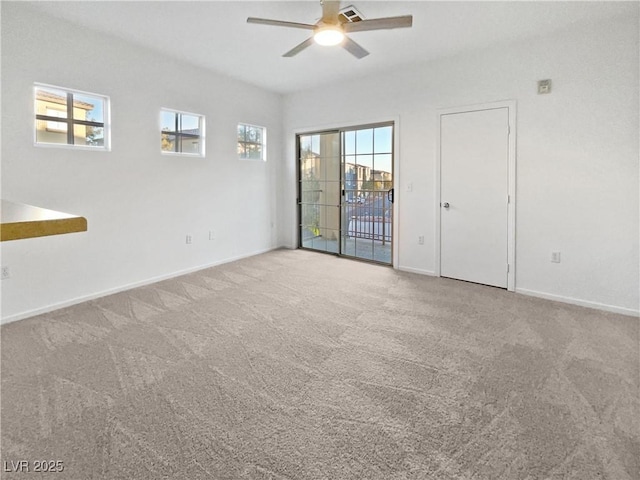 carpeted spare room featuring ceiling fan and a wealth of natural light