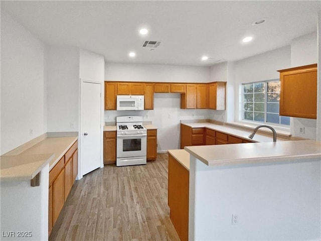 kitchen with sink, light hardwood / wood-style floors, kitchen peninsula, and white appliances