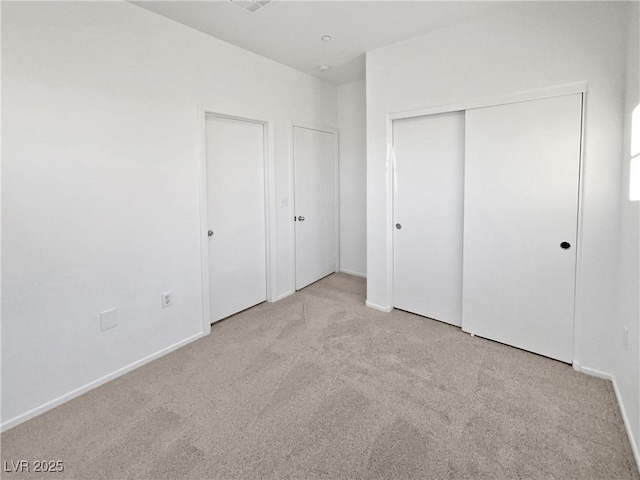 unfurnished bedroom featuring a closet and light colored carpet