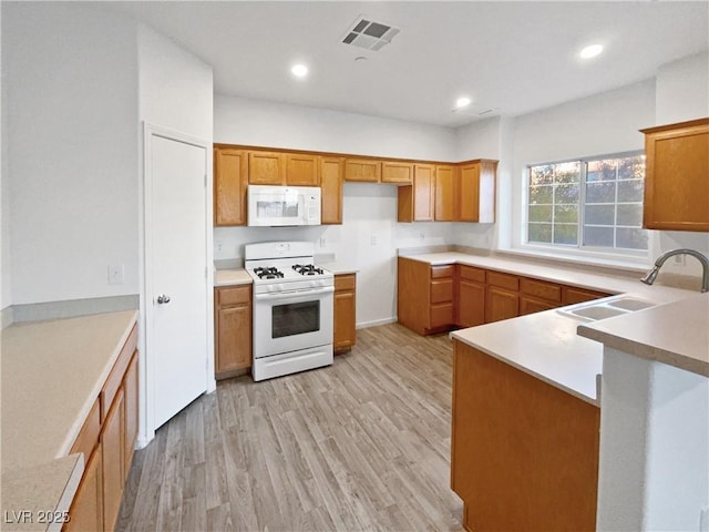 kitchen with sink, white appliances, and light hardwood / wood-style flooring