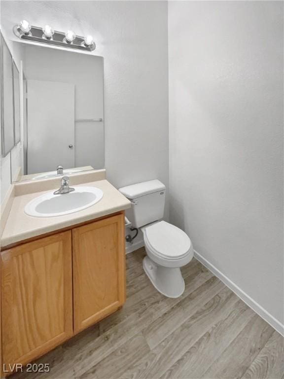 bathroom featuring toilet, vanity, and hardwood / wood-style floors