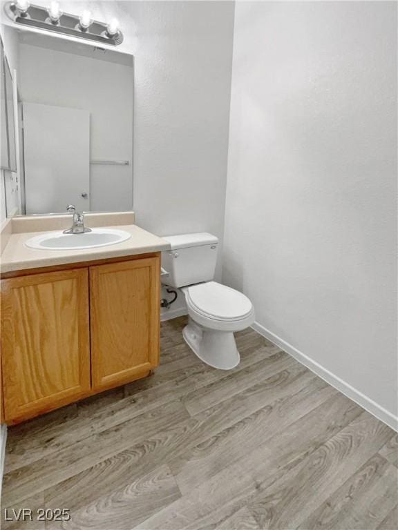 bathroom featuring toilet, hardwood / wood-style floors, and vanity