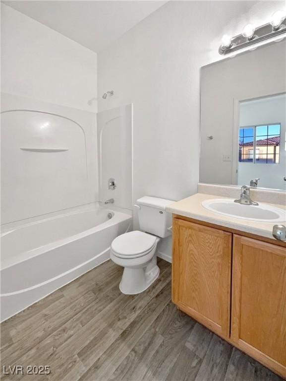 full bathroom with toilet,  shower combination, wood-type flooring, and vanity