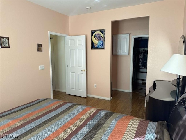 bedroom with dark wood-type flooring, a closet, and a walk in closet