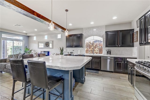 kitchen featuring stainless steel appliances, pendant lighting, a kitchen island, a breakfast bar, and beam ceiling