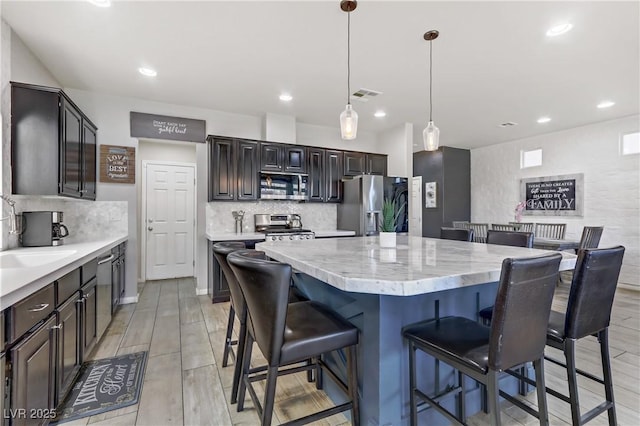 kitchen featuring a center island, decorative light fixtures, tasteful backsplash, appliances with stainless steel finishes, and dark brown cabinets