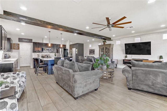 living room featuring beam ceiling, ceiling fan, and sink