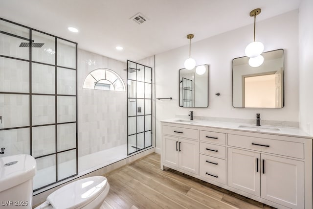 bathroom with tiled shower, vanity, and toilet