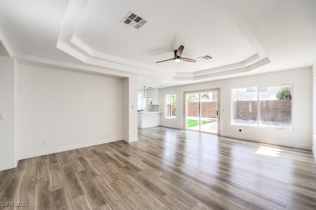 unfurnished living room featuring ceiling fan, light hardwood / wood-style flooring, and a raised ceiling