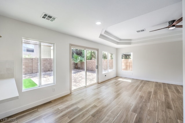 unfurnished room with ceiling fan, light hardwood / wood-style flooring, and a raised ceiling