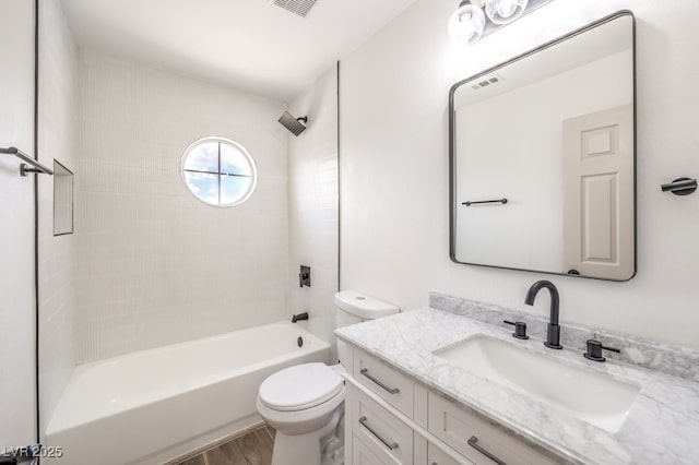 full bathroom featuring vanity, hardwood / wood-style flooring, tiled shower / bath combo, and toilet