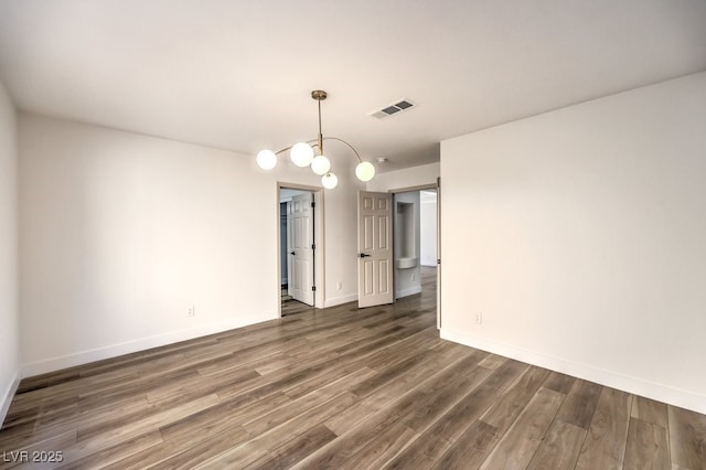 spare room featuring dark hardwood / wood-style flooring and a notable chandelier