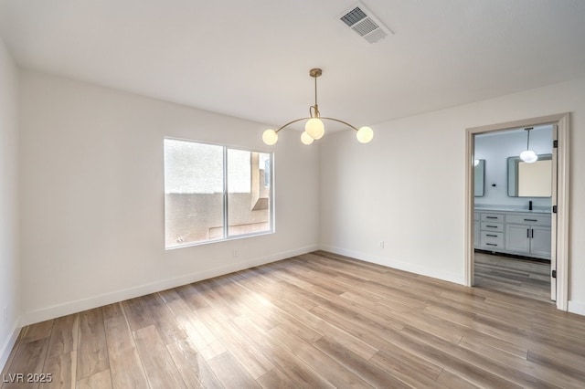 empty room with light hardwood / wood-style flooring and a chandelier