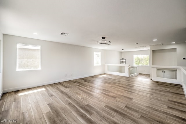 empty room with a notable chandelier and hardwood / wood-style flooring