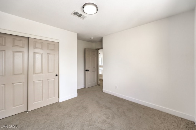 unfurnished bedroom with light colored carpet and a closet