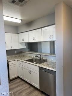 kitchen with sink, stainless steel dishwasher, dark hardwood / wood-style flooring, light stone countertops, and white cabinets