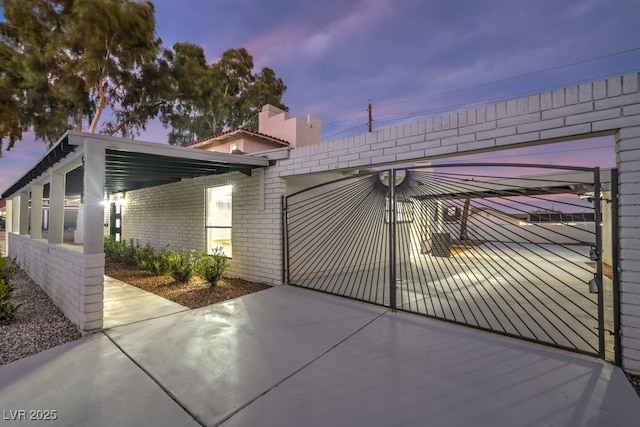 gate at dusk with a carport