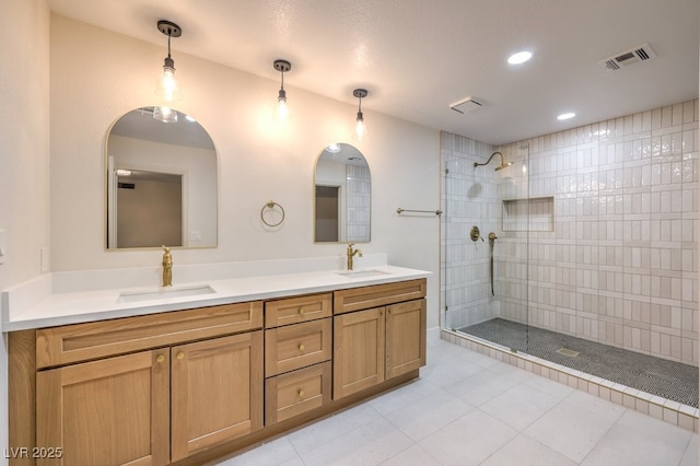 bathroom with tile patterned flooring, tiled shower, and vanity