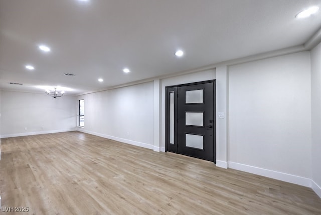 foyer entrance with an inviting chandelier, ornamental molding, and light hardwood / wood-style flooring