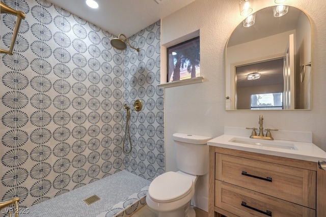 bathroom with toilet, vanity, and tiled shower