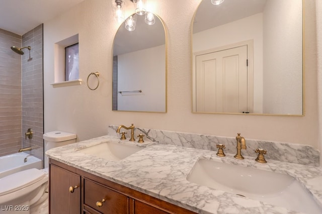 full bathroom with tiled shower / bath, vanity, and toilet