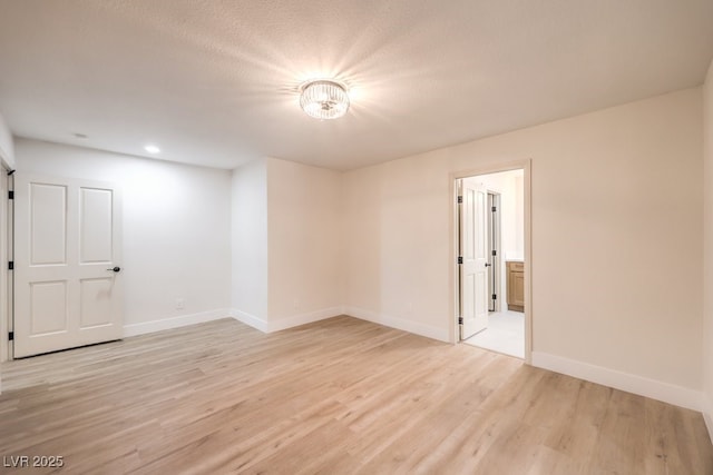 unfurnished room featuring light hardwood / wood-style floors and a textured ceiling