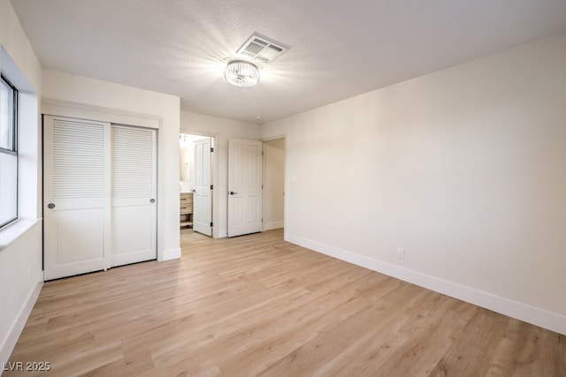 unfurnished bedroom with light wood-type flooring, a closet, and a textured ceiling