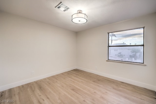 unfurnished room featuring light hardwood / wood-style floors and a textured ceiling