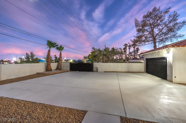 patio terrace at dusk featuring a garage