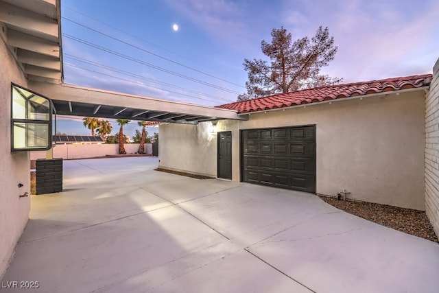 patio terrace at dusk featuring a garage