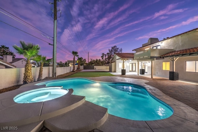 pool at dusk with central AC unit, an in ground hot tub, and a patio