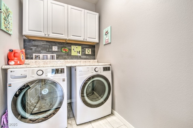 laundry room with light tile patterned flooring, washing machine and clothes dryer, and cabinets