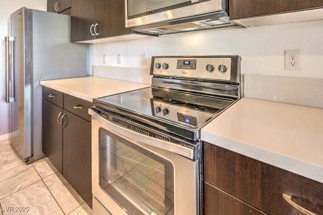 kitchen with appliances with stainless steel finishes, light tile patterned floors, and dark brown cabinets