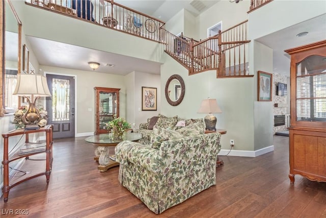 living room featuring a towering ceiling, dark hardwood / wood-style flooring, and a fireplace