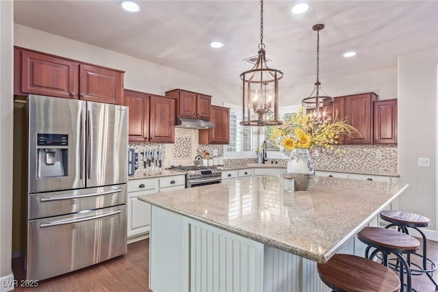 kitchen featuring a center island, a breakfast bar, an inviting chandelier, dark hardwood / wood-style flooring, and appliances with stainless steel finishes