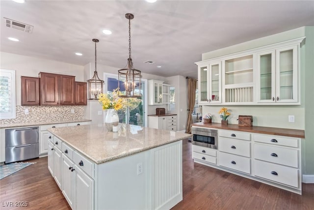 kitchen featuring pendant lighting, stainless steel appliances, decorative backsplash, a kitchen island, and white cabinetry