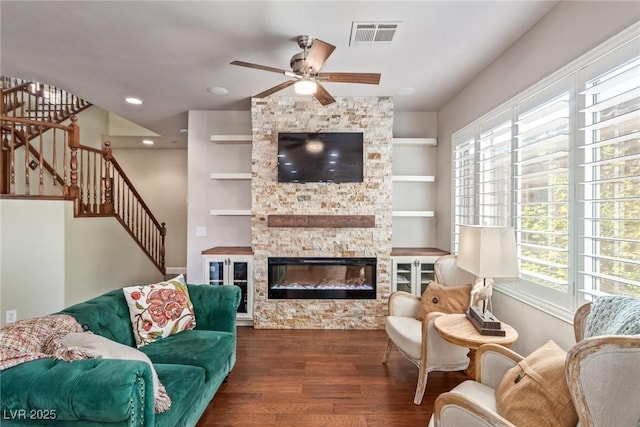 living room featuring a fireplace, dark wood-type flooring, built in shelves, and ceiling fan