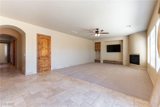 unfurnished living room featuring light colored carpet, ceiling fan, and plenty of natural light