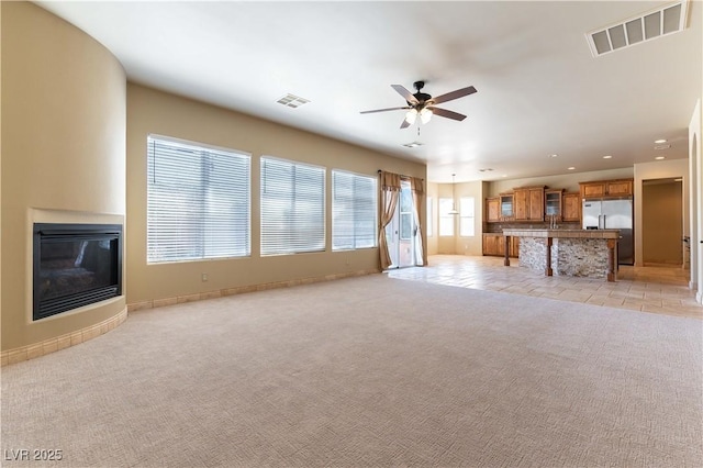 unfurnished living room with light carpet and ceiling fan