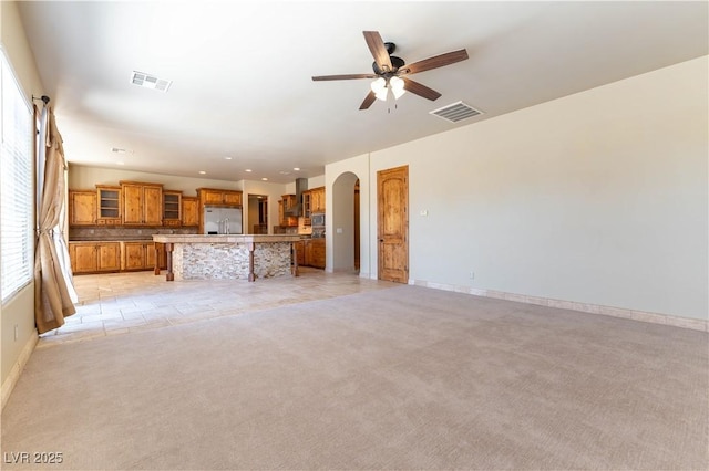 unfurnished living room featuring ceiling fan and light colored carpet